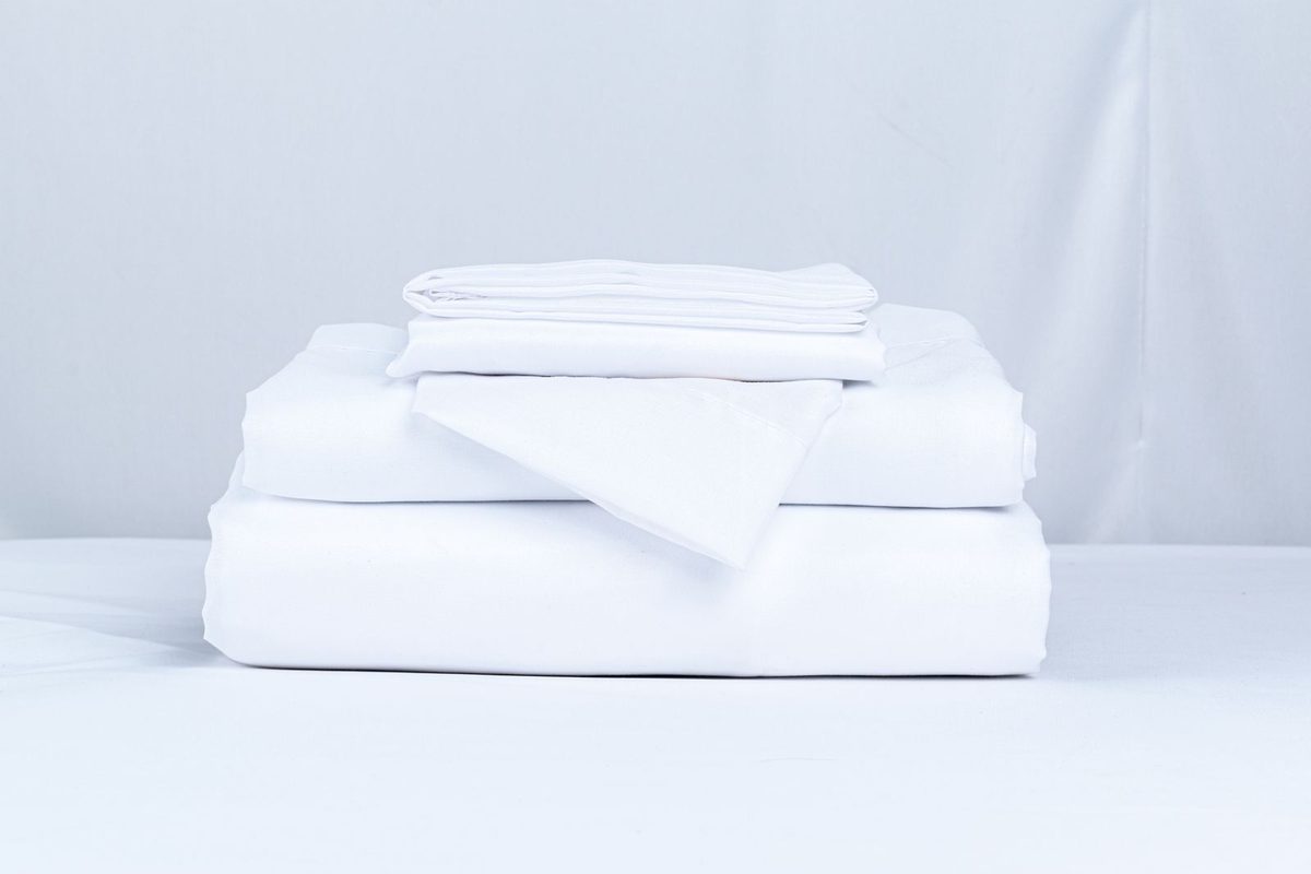A folded stack of white sheets and pillowcases